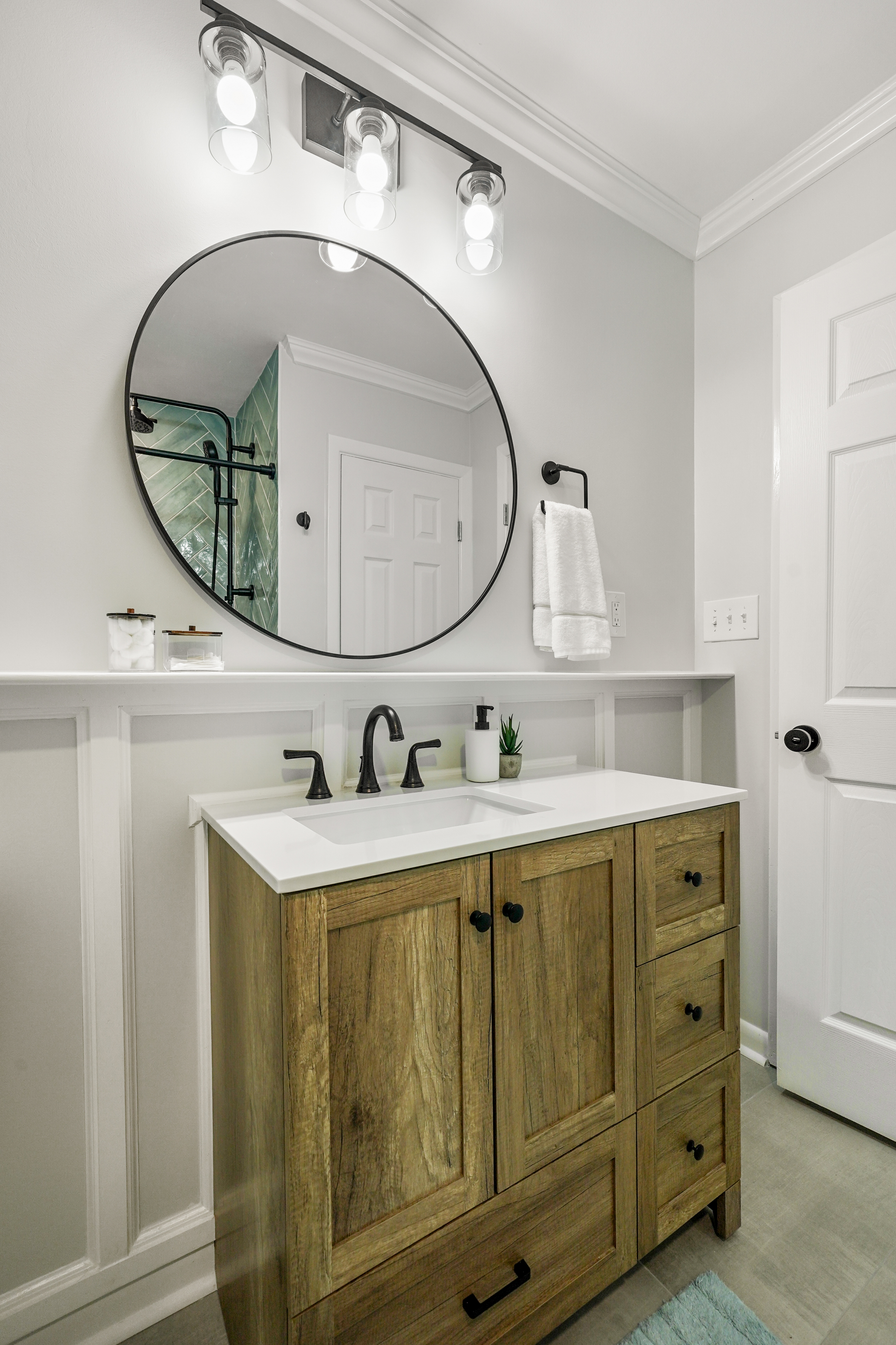 Bathroom with wood vanity and round mirror